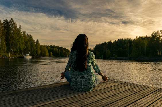 Photo of a woman meditating by a lake