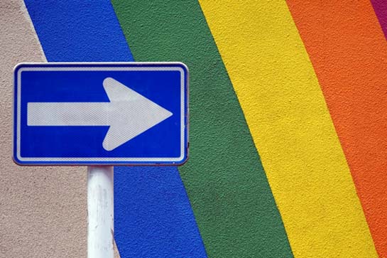 A street sign against a rainbow